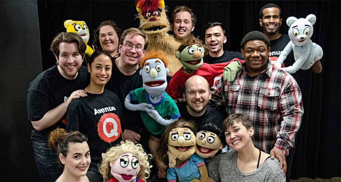 Students in theatre with puppets smiling at the camera to illustrate theatre 